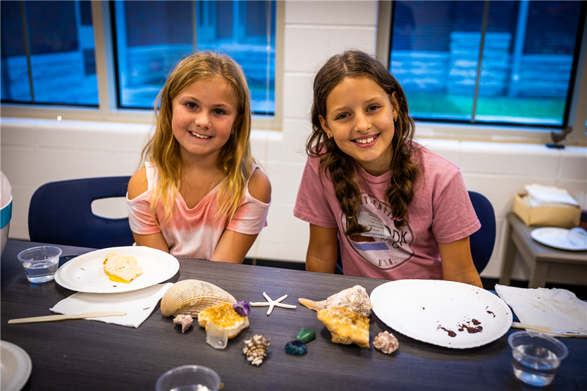 Two girls smile while sitting at a table
